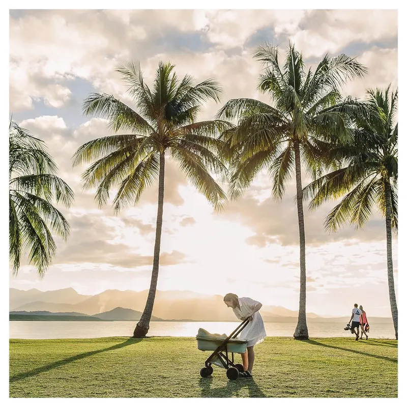 Greentom stroller lifestyle photograph of a woman with a pram under palm trees at sunset